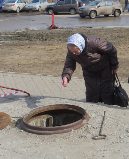 Elderly woman looks in the sewer